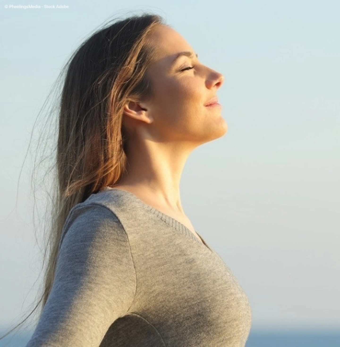 Alleinreisende Frau am Meer atmet tief ein