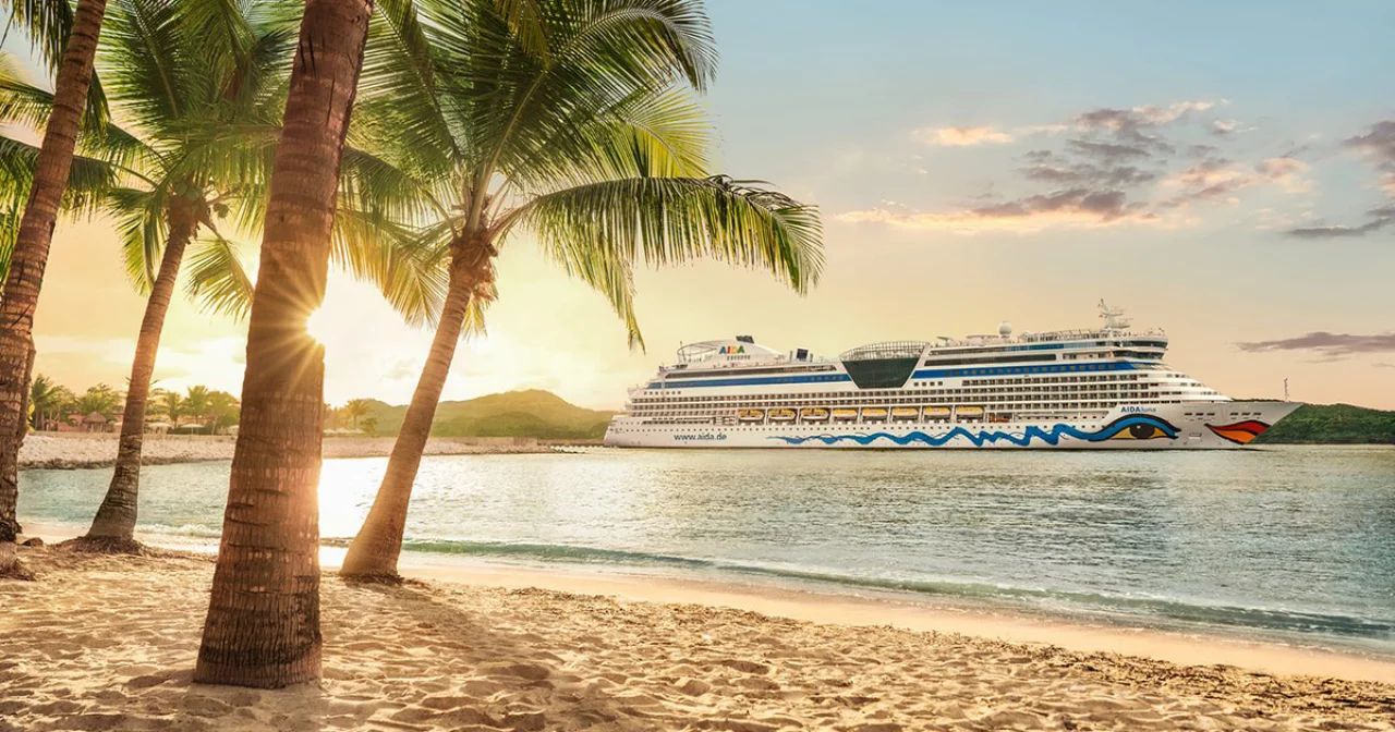 AIDA Schiff in der Karibik mit Traumstrand und Palmen im Vordergrund