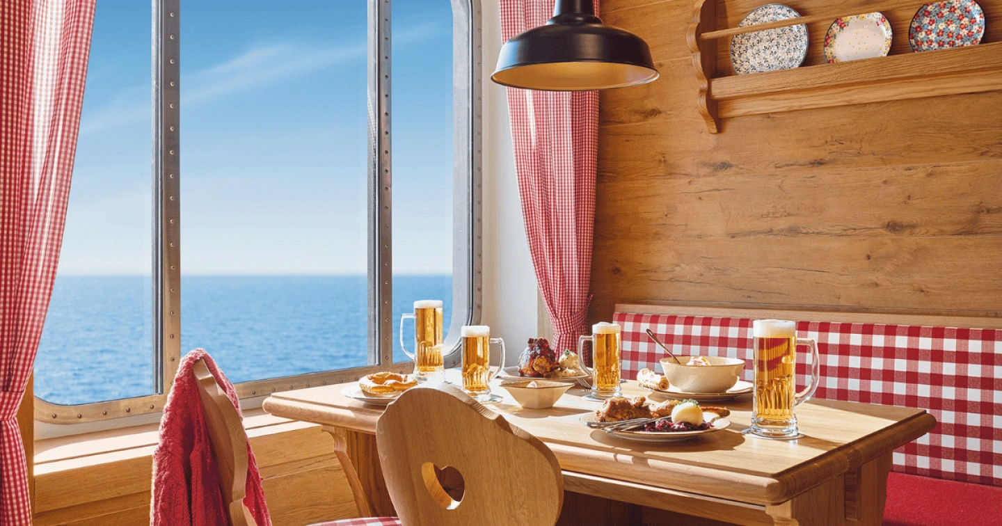 Gedeckter Tisch mit Essen und Trinken in AIDA Almhütte mit Meerblick.