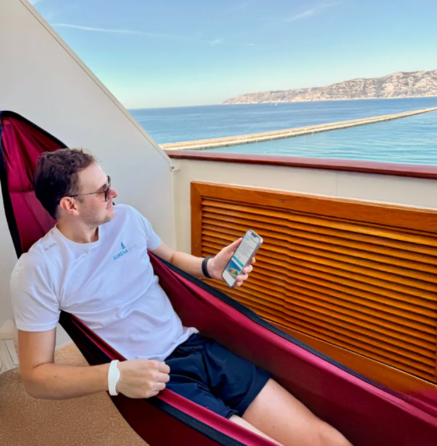 EURESAreisen Geschäftsführer Johannes mit Handy in Hängematte an Bord von AIDA Schiff