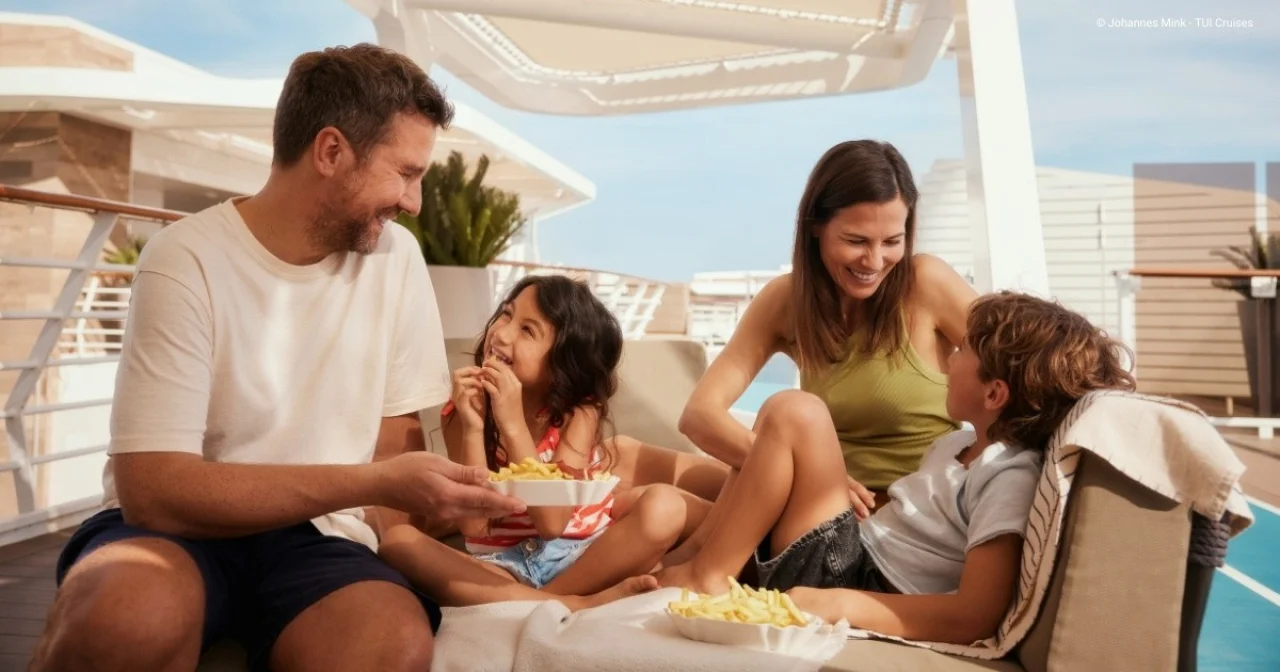 Fröhliche Familie isst Pommes auf Außendeck an Bord der Mein Schiff 1
