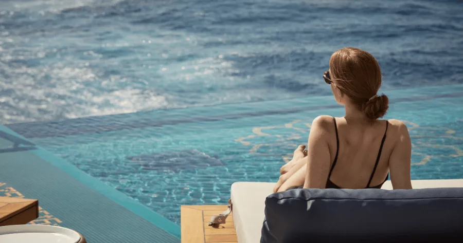 Frau auf Liege am Astern Pool von Explora I schaut aufs Meer