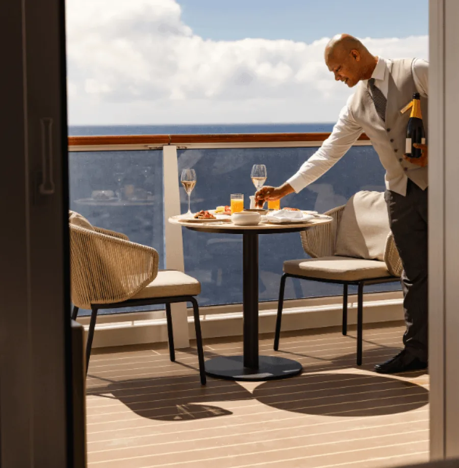 Butler auf Explora Kreuzfahrtschiff serviert Champagner auf Suitenbalkon