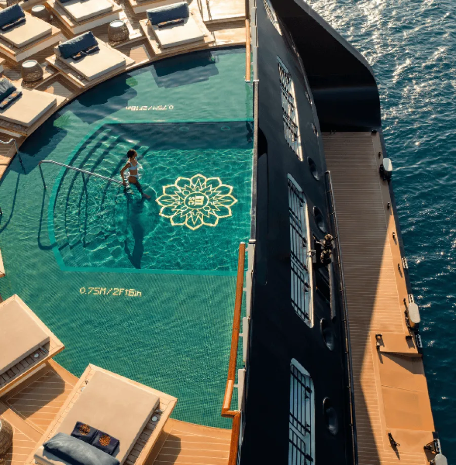 Frau steigt über Treppe in Pool am Heck eines Luxus-Kreuzfahrtschiffes von Explora Journeys
